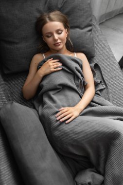 Güzel beyaz kadın evdeki kanepede uyuyor ve güzel rüyalar görüyor. Sağlıklı, iyi uykular. en üstteki görünüm