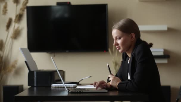 Flicka arbetar hemifrån på en fjärrdator vid ett skrivbord med en bärbar dator — Stockvideo