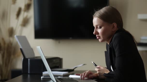 Κορίτσι κάνει εργασία από το σπίτι σε ένα απομακρυσμένο υπολογιστή σε ένα γραφείο με ένα σημειωματάριο — Αρχείο Βίντεο