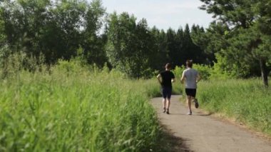 Spor giyimli erkekler parkta koşuyor. Açık hava sporları.