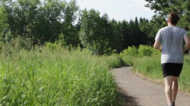 Spor giyimli erkekler parkta koşuyor. Açık hava sporları.