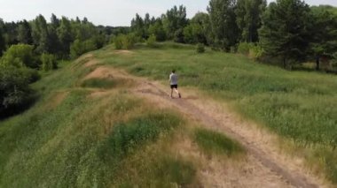 Spor giyimli bir adam parkta koşuyor. İHA saldırısı. Açık hava sporları.