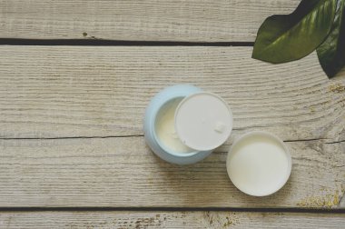 beyaz ahşap masa arka plan üzerinde yüz kremi. Çiçeklerile beyaz ahşap arka plan üzerinde Kozmetik krem konteyner. Yüz kremi afiş.