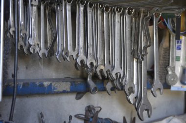 Garajda eski kirli aletler. Oto atölyesinde anahtarlar, kancalar üzerinde tam set