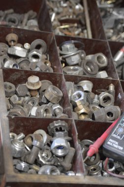 Bir dizi somun, araba atölyesindeki kutuda vidalar. Çekmecedeki ammetre ve vidalar ve cıvatalar