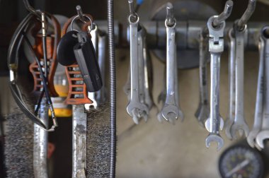 Garajda eski kirli aletler. Oto atölyesinde anahtarlar, kancalar üzerinde tam set