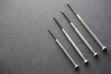 Kalın gri çizim defteri kağıt üzerinde ekipman tamir için küçük tornavidalar. Kalın gri kağıt dokusu