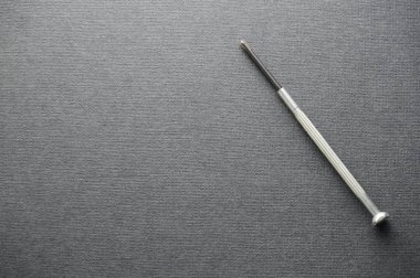 Kalın gri çizim defteri kağıt üzerinde ekipman tamir için küçük tornavidalar. Kalın gri kağıt dokusu