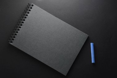 Siyah bir arka plan üzerinde parlak çok renkli tebeşir. Kalem veya tebeşir çizmek için eskiz defteri koyu bir arka plan üzerinde yatıyor