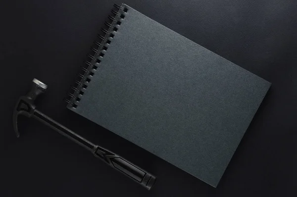 Isolated black hammer and black gray note book on black matte background