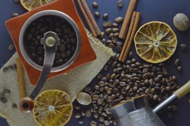 Kahve çekirdekleri ve tarçın çubukları ve portakal dilimleri ile, koyu mavi arka plan üzerinde bir manuel kahve öğütücü