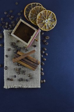 Taze doğal kahve çekirdekleri tarçın çubukları, dilimlenmiş portakal dilimleri ile koyu mavi bir arka plan üzerinde dağınık