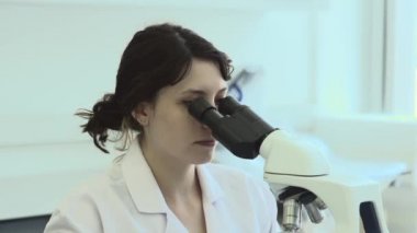 Kafkas bilim adamı laboratuvarda araştırma, mikroskop üzerinden bakarak ve notlar alarak