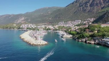 Drone shot of a blue sea and Port with boats going in and out to marina. Mountains at background Kas Turkey