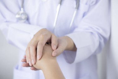 Dost canlısı doktorun elleri hastayı cesaretlendirmek ve güvenini kazanmak için ellerini tutar.