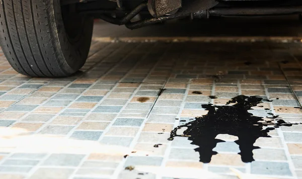 Oil leaks or drops from the car\'s engine on the parking lot. Car inspection and maintenance service