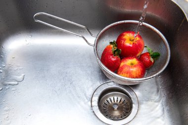 Mutfak lavabosunda meyve yıkıyorum. 