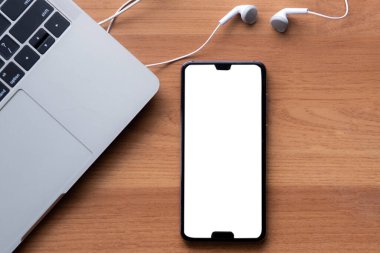 Akıllı telefon ekranı boş kulaklıklar ve tahta arka planda bilgisayar defteri
