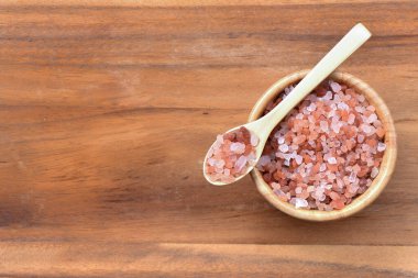 Himalayan salt Placed on a spoon and in a bowl on wood background clipart