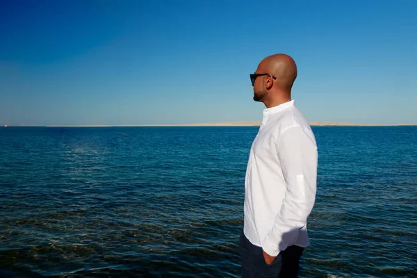 Siyah gözlüklü yakışıklı, beyaz gömlekli, güçlü yakışıklı adam güneşli yaz gününde güneşli bir deniz seyahatinin tadını çıkarıyor. Yüz profili yakın plan Orta Doğu erkek portresi. Mısır