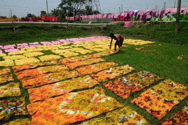 Bir Bangladeşli çocuk işçi Dhaka yakın Narsingdi alanda Batik kumaş sektöründe güneş altında bezeler kurutur, Bangladeş, Nisan 'da 26, 2018. Her Işçi par gün 400-500 taka veya 5-6 ABD doları kazanır.