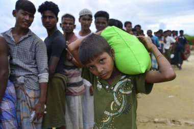 Rohingya mültecileri, 7 Ekim 2017 'de Teknaf, Bangladeş' teki Mowsuni yardım kampından toplanan yardım yardımlarını taşıyorlar. 582 bin Rohingyalı mülteci Myanmar 'daki evlerinden kaçtı ve ağustos sonundan bu yana Bangladeş' e geldi.
