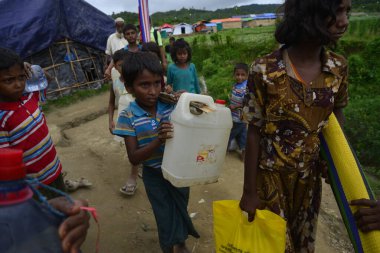 Bir Rohingya çocuğu, 7 Eylül 2017 'de Bangladeş, Cox' s Bazar 'daki Unchiprang derme çatma kampında içme suyu taşır. Birleşmiş Milletler Mülteciler Yüksek Komiserine (UNHCR) göre 525 binden fazla Rohingyalı mülteci Myan 'dan kaçtı