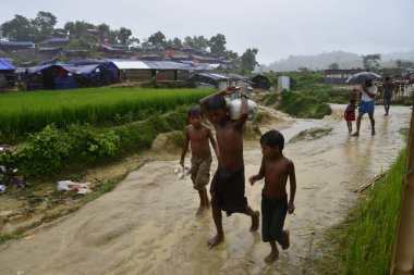 Rohingya mültecisi, 7 Eylül 2017 'de Bangladeş, Cox' s Bazar 'daki Unchiprang derme çatma kampında yağmurda yürüyor. Birleşmiş Milletler Mülteciler Yüksek Komiserine (UNHCR) göre 525.000 'den fazla Rohingyalı mülteci Myanm' dan kaçtı