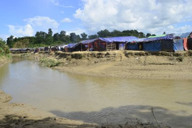 Rohingya mültecileri 10 Ekim 2017 'de Tombru Bandarban' ın Myanmar ve Bangladeş sınırları arasındaki tarafsız bölge yakınlarındaki bir yerleşim bölgesinin yanındaki kanalı geçtiler. Myanmar 'da şiddetten kaçan binlerce Rohingya Ban' a akın etti