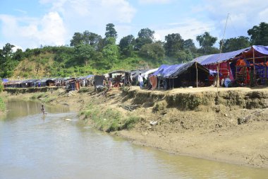 Rohingya mültecileri 10 Ekim 2017 'de Tombru Bandarban' ın Myanmar ve Bangladeş sınırları arasındaki tarafsız bölge yakınlarındaki bir yerleşim bölgesinin yanındaki kanalı geçtiler. Myanmar 'da şiddetten kaçan binlerce Rohingya Ban' a akın etti
