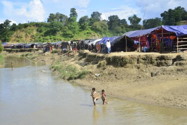 Rohingya mültecileri 10 Ekim 2017 'de Tombru Bandarban' ın Myanmar ve Bangladeş sınırları arasındaki tarafsız bölge yakınlarındaki bir yerleşim bölgesinin yanındaki kanalı geçtiler. Myanmar 'da şiddetten kaçan binlerce Rohingya Ban' a akın etti