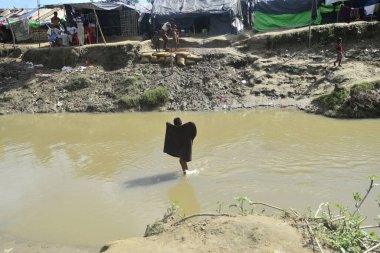 Rohingya mültecileri 10 Ekim 2017 'de Tombru Bandarban' ın Myanmar ve Bangladeş sınırları arasındaki tarafsız bölge yakınlarındaki bir yerleşim bölgesinin yanındaki kanalı geçtiler. Myanmar 'da şiddetten kaçan binlerce Rohingya Ban' a akın etti