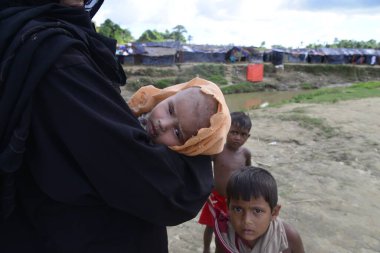 10 Ekim 2017 'de, Tombru Bandarban' ın Myanmar ve Bangladeş sınırları arasındaki tarafsız bölge yakınlarında bir Rohingya mülteci kadın çocuklarıyla birlikte derme çatma bir kampta poz verdi. Binlerce Rohingya 'nın şiddetten kaçması