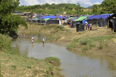 Rohingya mültecileri 10 Ekim 2017 'de Tombru Bandarban' ın Myanmar ve Bangladeş sınırları arasındaki tarafsız bölge yakınlarındaki bir yerleşim bölgesinin yanındaki kanalı geçtiler. Myanmar 'da şiddetten kaçan binlerce Rohingya Ban' a akın etti