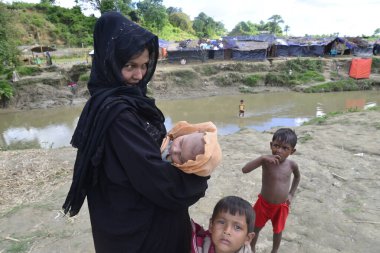 10 Ekim 2017 'de, Tombru Bandarban' ın Myanmar ve Bangladeş sınırları arasındaki tarafsız bölge yakınlarında bir Rohingya mülteci kadın çocuklarıyla birlikte derme çatma bir kampta poz verdi. Binlerce Rohingya 'nın şiddetten kaçması