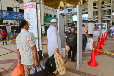 Yolcu, 24 Haziran 2020 'de Bangladeş, Dhaka' da meydana gelen koronavirüs salgını sırasında Kamalapur Tren İstasyonu 'ndaki vücut sıcaklığını ölçmek için elektronik kapıdan geçerken maske takıyor.