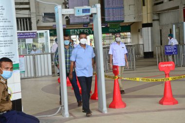 Yolcu, 24 Haziran 2020 'de Bangladeş, Dhaka' da meydana gelen koronavirüs salgını sırasında Kamalapur Tren İstasyonu 'ndaki vücut sıcaklığını ölçmek için elektronik kapıdan geçerken maske takıyor.