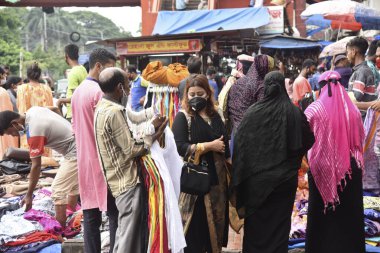 Yüz maskesi takan insanlar, 28 Haziran 2020 'de Bangladeş, Dhaka' daki koronavirüs salgını sırasında ihtiyaçlarını satın almak için bir sokak pazarında toplandılar.