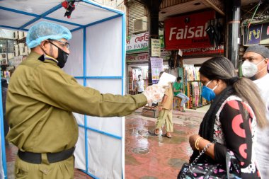 Bir güvenlik görevlisi, 28 Haziran 202 'de Bangladeş, Dhaka' daki koronavirüs salgını sırasında alışveriş merkezinin girişindeki vücut ısısını kontrol ediyor.