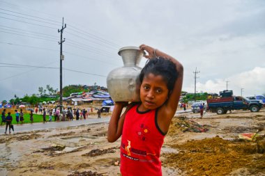 Bir Rohingya mültecisi çocukları Bangladeş 'in Cox Çarşısı' ndaki Thengkhali derme çatma kampında 2006 Eylül 'ünde su taşır. Ağustos ayında komşu Myanmar 'a yapılan askeri baskından bu yana 600 binden fazla Rohingya Bangladeş' e geldi.