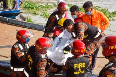 Kurtarma ekipleri 29 Haziran 2020 'de Bangladeş' in Dhaka kentindeki Buriganga Nehri 'nde alabora olan fırlatmanın ardından kurbanların cesetlerini taşıyorlar. Dhaka Coll 'daki Sadarghat feribot terminalinde bir feribot alabora olup battıktan sonra en az 30 kişi öldü ve bir düzinesi kayıp.