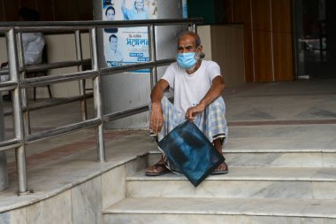 Dhaka, Bangladeş 'teki koronavirüs salgını sırasında Dhaka Tıp Fakültesi Hastanesi' nin önünde 3 Temmuz 2020 tarihinde bir hasta doktor tavsiyesi için röntgen filmiyle bekliyor..