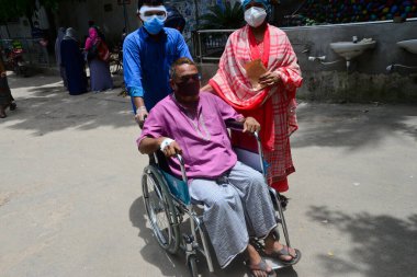 Bir hasta, Bangladeş, Dhaka 'daki koronavirüs salgını sırasında tedavi görmek için 3 Temmuz 2020' de Dhaka Tıp Fakültesi Hastanesi 'nin önünde akrabalarıyla birlikte bekliyor..