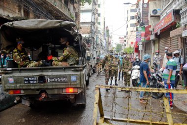 Bangladeş Ordusu askerleri ve polisi, Bangladeş 'in başkenti Dhaka' da bulunan Wari 'de, 4 Temmuz 2020' de hükümet tarafından azami enfeksiyon riski bulunan koronavirüs kırmızı bölgesinde devriye gezerken evlerinde kalacaklarının farkında.