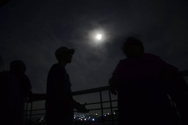 6 Temmuz 2020 'de Bangladeş' teki koronavirüs salgını sırasında insanlar Dhaka şehrindeki bir binanın çatısından dolunayın keyfini çıkarıyorlar.