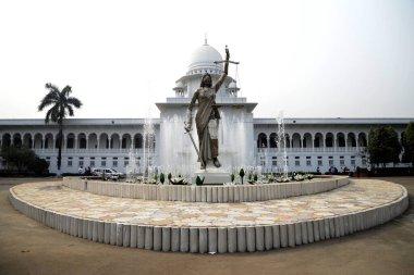 28 Ocak 2017 'de Bangladeş' in Dhaka kentindeki Anayasa Mahkemesi kompleksinin önünde duran bir Adalet Heykeli. Elinde terazi ve kılıç tutan bir kadın heykeli Aralık ayında mahkeme binasının dışına dikildi. Heykel sarıldı. 