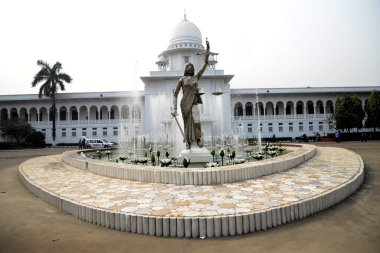 28 Ocak 2017 'de Bangladeş' in Dhaka kentindeki Anayasa Mahkemesi kompleksinin önünde duran bir Adalet Heykeli. Elinde terazi ve kılıç tutan bir kadın heykeli Aralık ayında mahkeme binasının dışına dikildi. Heykel sarıldı. 