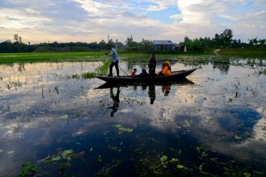 Bangladeş köylüleri 16 Temmuz 2020 'de Jamalpur İlçesi' ndeki evlerine giden bir tekneyle sel sularını geçerler.