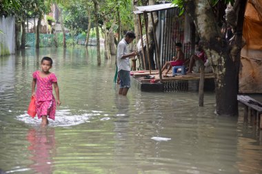 24 Temmuz 2020 'de Bangladeş' in Dhaka kenti yakınlarındaki Manikganj 'daki sel sularından köy çocukları geçtiler. Güney Asya 'da şiddetli muson yağmurlarından kaynaklanan ölüm bilançosu yaklaşık 200' e yükseldi. Neredeyse dört milyon insan muson seli tarafından vuruldu.