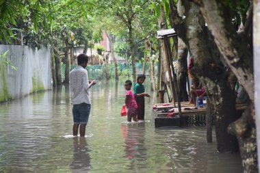 24 Temmuz 2020 'de Bangladeş' in Dhaka kenti yakınlarındaki Manikganj 'daki sel sularından köy çocukları geçtiler. Güney Asya 'da şiddetli muson yağmurlarından kaynaklanan ölüm bilançosu yaklaşık 200' e yükseldi. Neredeyse dört milyon insan muson seli tarafından vuruldu.